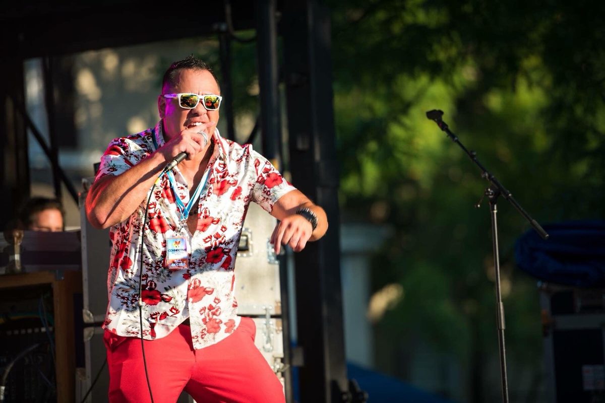 Moe emceeing on an outdoor festival stage, microphone in hand