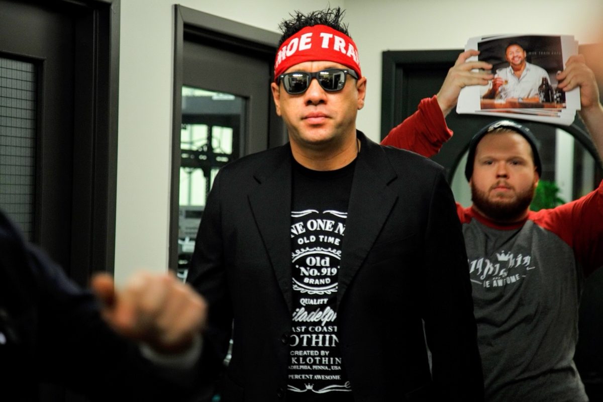 Moe arriving at Wing Bowl in a blazer, sunglasses, and Moe Train headband with his entourage