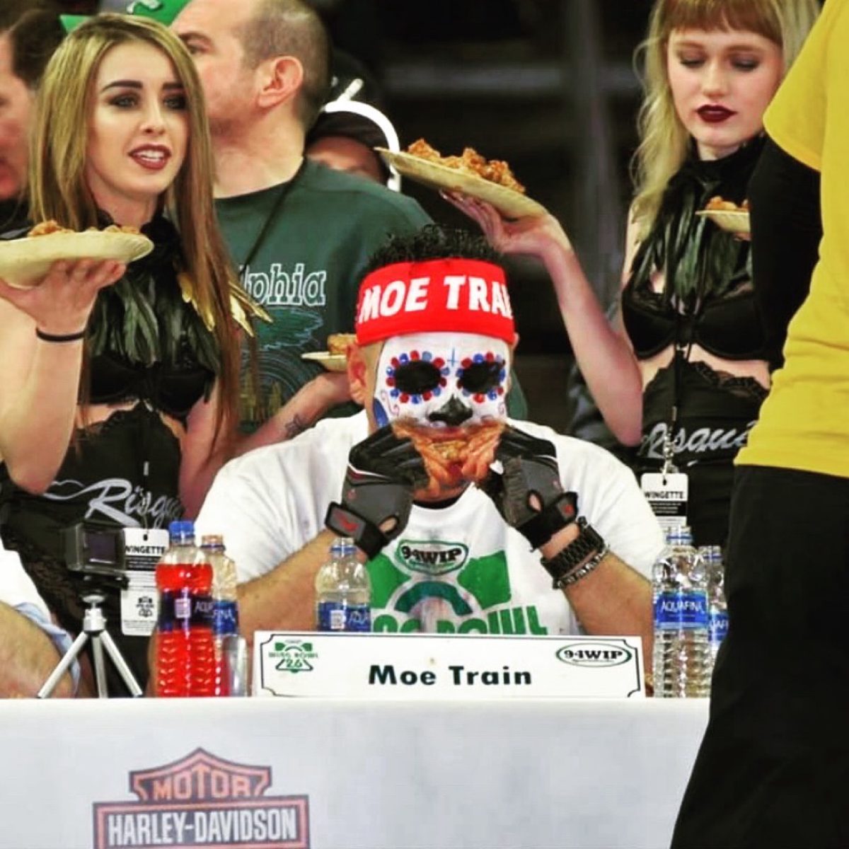 Moe eating wings at the Wing Bowl table with his Moe Train nameplate