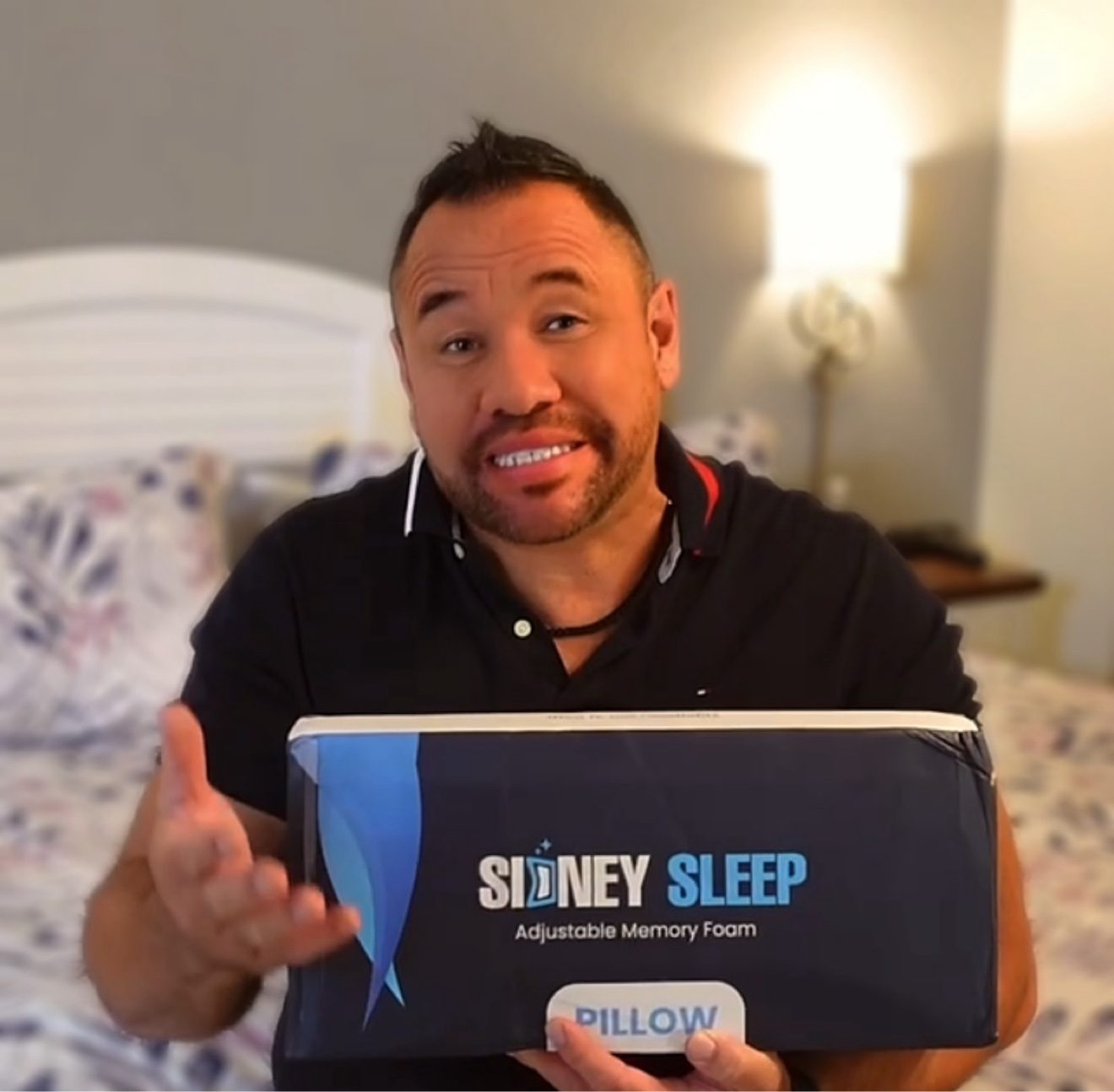 Moe presenting a Sidney Sleep adjustable memory foam pillow box in a bedroom